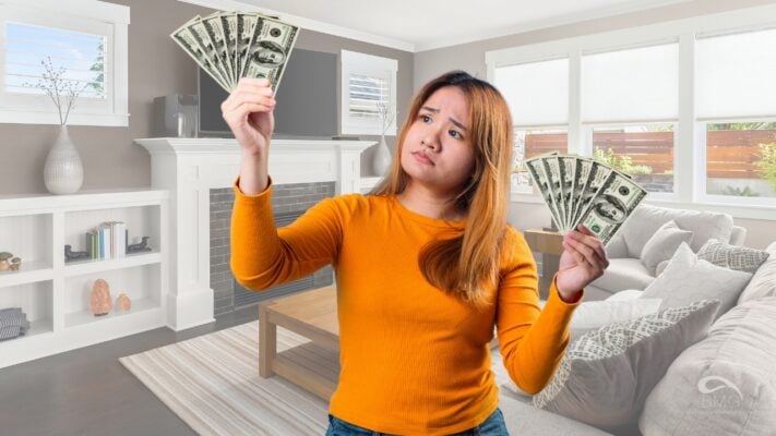 Woman in a living room holding cash in both hands, looking confused about rental costs or budgeting concerns