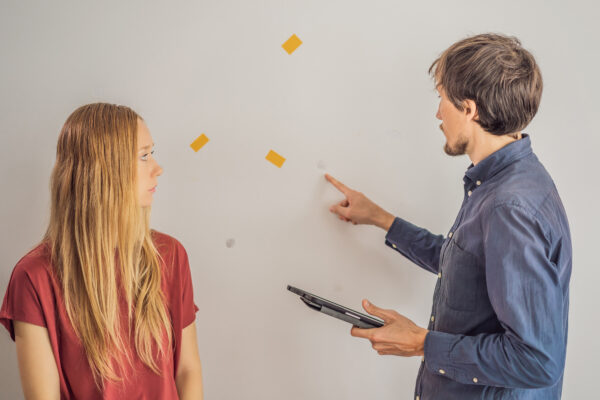 A landlord points out wall damage to a tenant while checking for rental property damage.