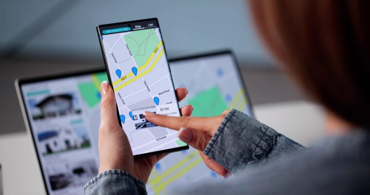 Person comparing rental property listings online using a smartphone and laptop