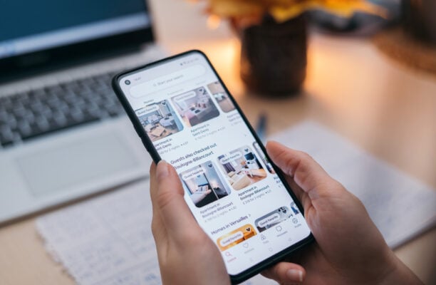 Person searching apartment rental listings on a smartphone during the housing application process