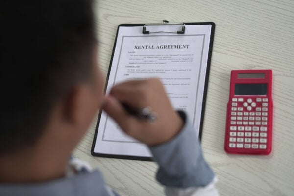 Tenant reviewing rental agreement and calculating unpaid rent after collections notice