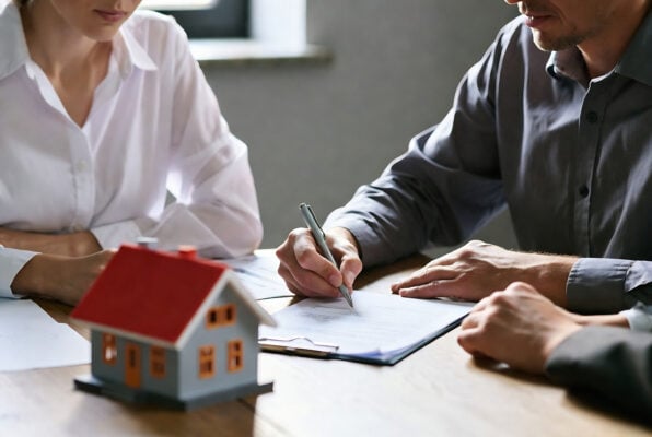 People reviewing and signing rental paperwork during a professional property management meeting